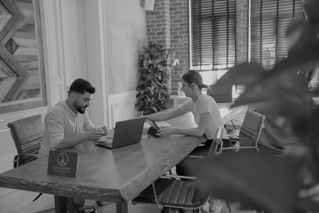 Dos personas trabajando en una mesa de reuniones
