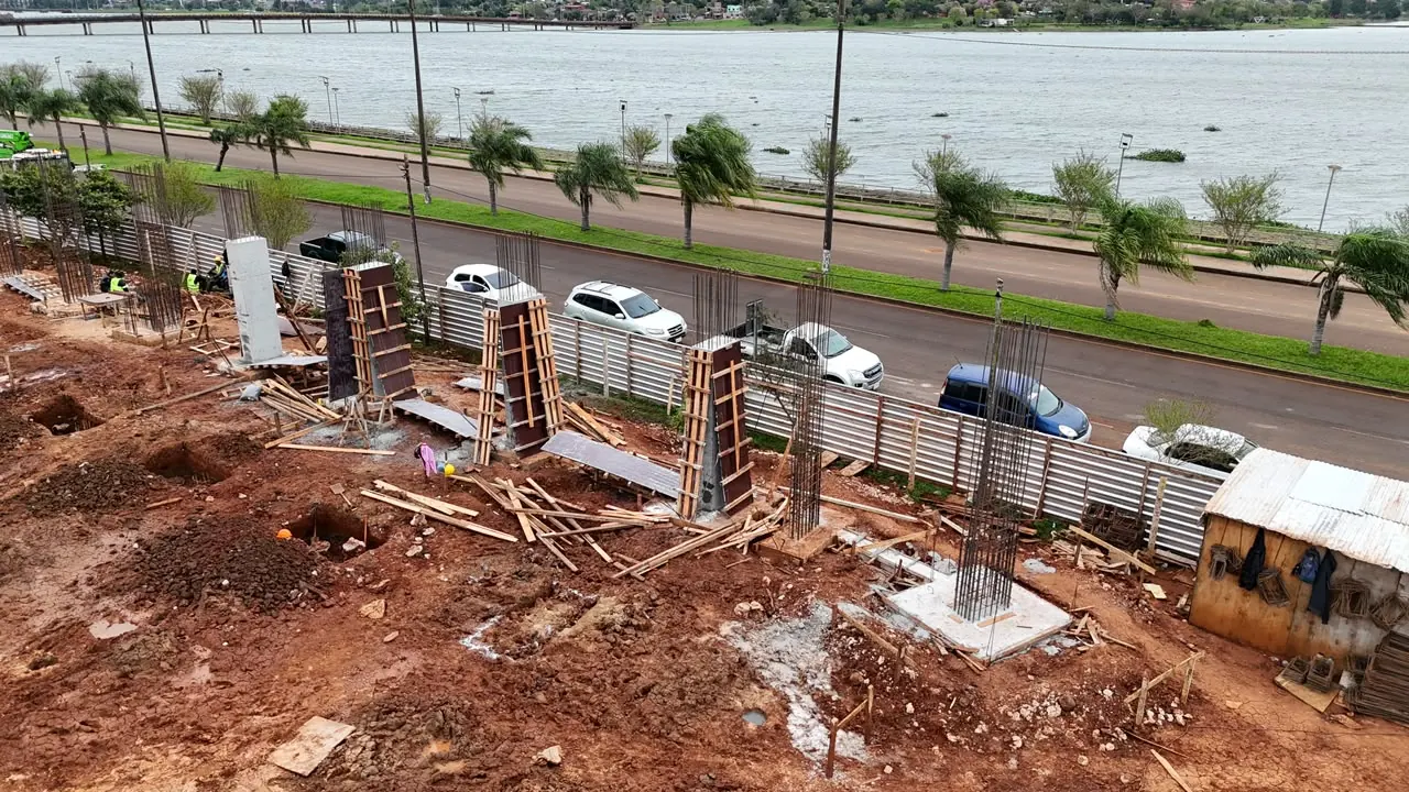 La obra del Centro de Alto Rendimiento sobre la costanera de Encarnación: columnas de hormigón encofradas y armaduras montadas, con el río al fondo.