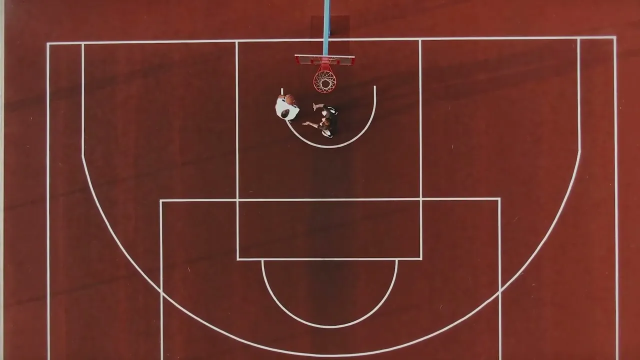 Vista aérea de una cancha de básquet con dos chicos jugando bajo el aro