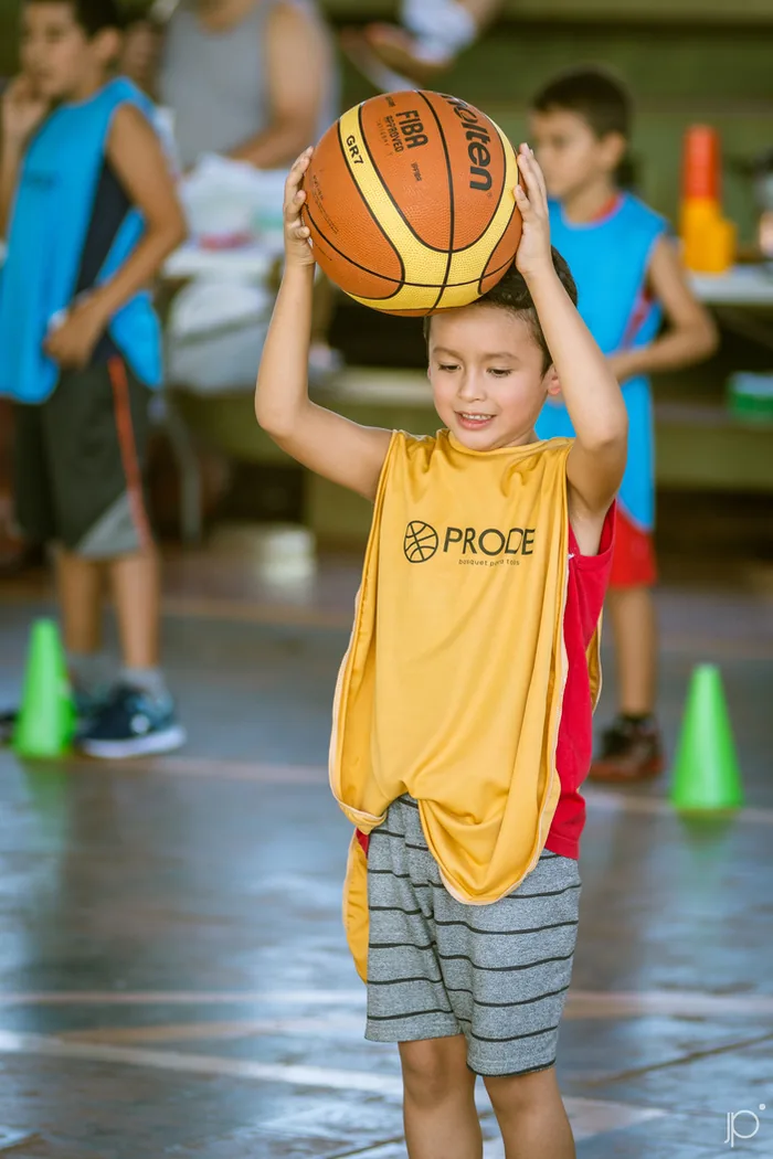 Un chico con la camiseta del PRODE levantando una pelota de básquet por encima de la cabeza