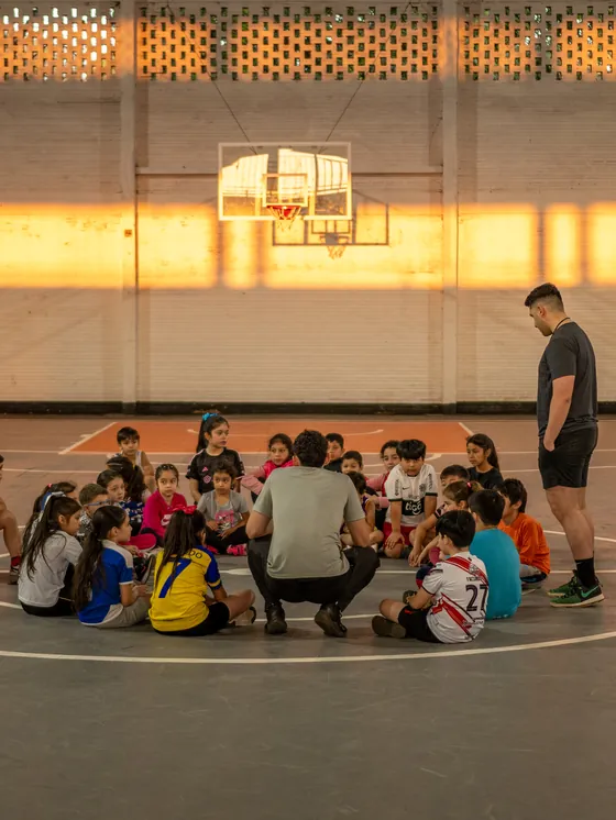 Una cancha amplia y casi vacía, con un grupo reunido en un extremo.
