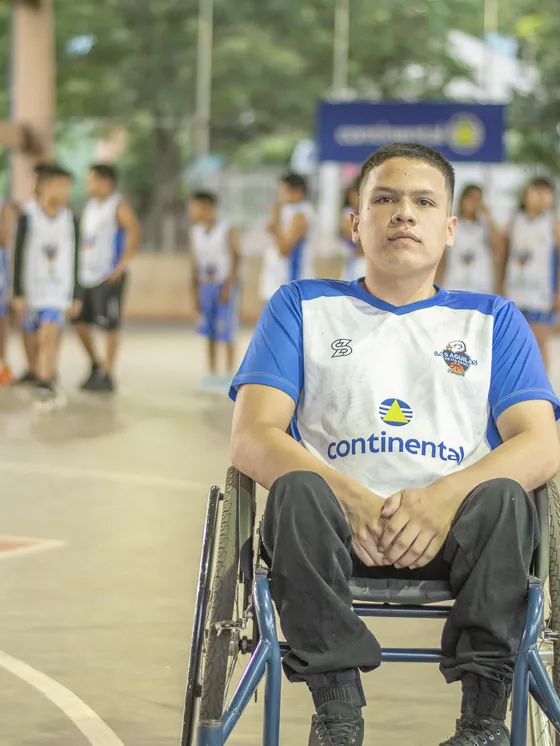 Un jugador en silla de ruedas en el centro de la cancha, con el equipo al fondo.
