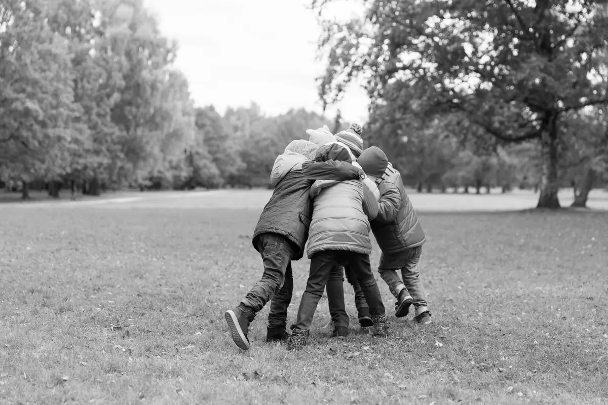 Un grupo de chicos abrazados de espaldas, en un parque
