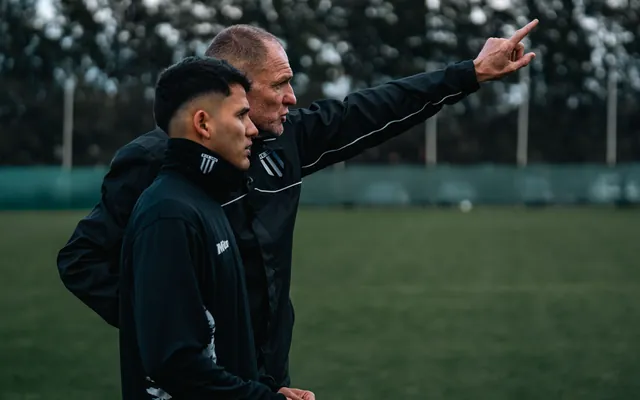 Dos entrenadores al costado de la cancha, uno señalando