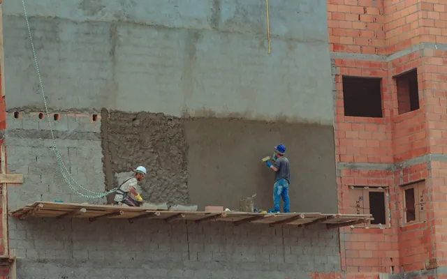 Dos albañiles revocando la pared de una obra
